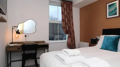 a room with a bed and a desk and a window at Braithwaite House Rooms in Braithwaite