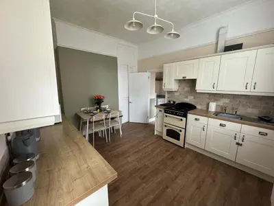 a kitchen with white cabinets and a table in it at Ennerdale Edge - 4 Bedrooms - Sleeps 8 in Cleator Moor