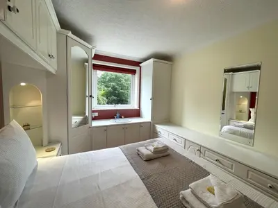 a bedroom with a large white bed and a window at Traditional Scottish Cottage in Beautiful Location - Pass the Keys in Rockcliffe