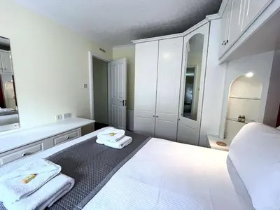 a white bedroom with a bed and a mirror at Traditional Scottish Cottage in Beautiful Location - Pass the Keys in Rockcliffe