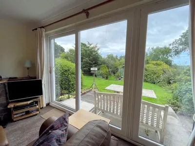 a living room with a large sliding glass door at Traditional Scottish Cottage in Beautiful Location - Pass the Keys in Rockcliffe
