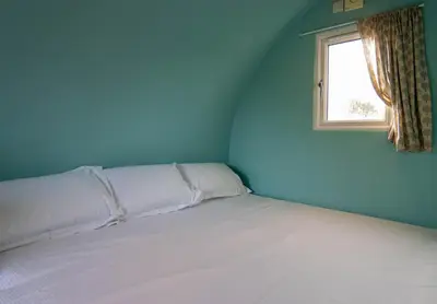 a bed in a blue room with a window at Broom Leisure Camping Pods in Annan