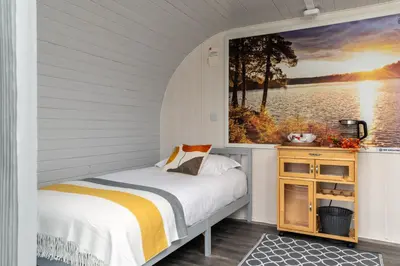 a bedroom with a bed and a painting on the wall at Broom Leisure Camping Pods in Annan