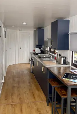 a large kitchen with blue cabinets and a wooden floor at Lagavulin 3 in Portpatrick