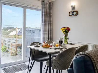 a dining room with a table and chairs and a window at Anchor Cottage in Portpatrick
