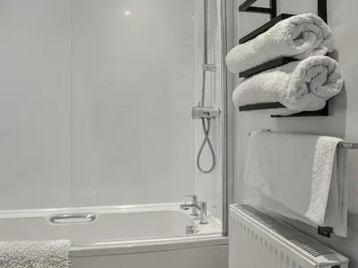 a bathroom with a shower with towels and a sink at Anchor Cottage in Portpatrick