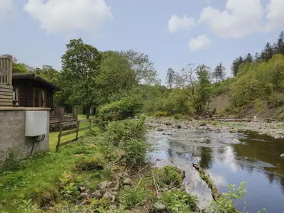 a river next to a building and a house at Elm Lodge in Keswick