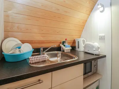 a kitchen with a sink and a wooden wall at Pod No 6 in Keswick
