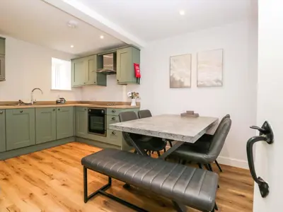 a kitchen with green cabinets and a table and chairs at Riverside Cottage No 4 in Keswick
