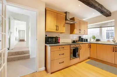 a kitchen with wooden cabinets and a sink and a microwave at Hummingbird House in Cockermouth