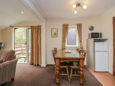 a dining room with a table and a refrigerator at Beech Timber Lodge in Keswick