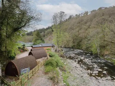 a river with two huts next to a river at Canadian Cabin No 39 in Keswick