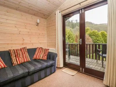 a living room with a couch and a balcony at Canadian Cabin No 39 in Keswick