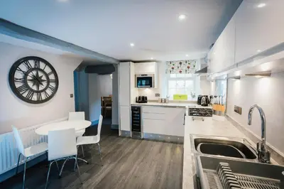 a kitchen with a table and chairs and a clock on the wall at Greta House in Keswick