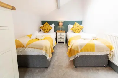 a bedroom with two beds with yellow and white blankets at Briery House in Keswick
