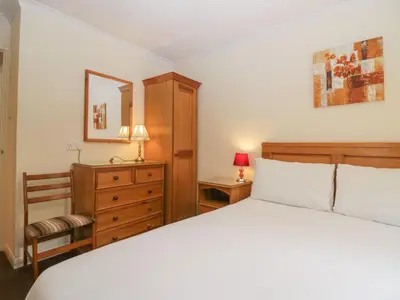a bedroom with a bed and a chair and a dresser at Chestnut Timber Lodge in Keswick