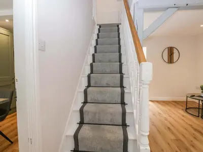 a stairway in a home with white walls and wood floors at Riverside Cottage No 5 in Keswick