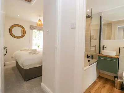 a bedroom with a bed and a bathroom with a shower at Riverside Cottage No 5 in Keswick