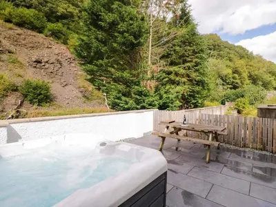 a hot tub with a picnic table and a bench at Riverside Cottage No 5 in Keswick