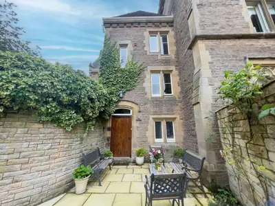 a brick house with two benches and a wooden door at Geltsdale Wing, Wetheral 1st floor apartment with countryside views, close to pub & restaurant in Wetheral