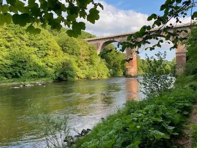 a bridge over a river next to a river at Geltsdale Wing, Wetheral 1st floor apartment with countryside views, close to pub & restaurant in Wetheral