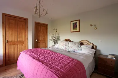 a bedroom with a pink blanket on a bed at Knockaloe Beg Farm in Patrick
