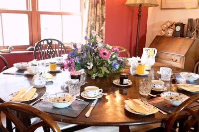 a wooden table with a vase of flowers on it at Knockaloe Beg Farm in Patrick
