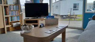 a living room with a tv and a coffee table at Arual Caravan Manor House Park. Allonby, Cumbria in Maryport