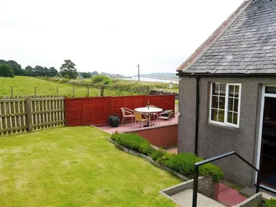 a small backyard with a table and a fence at Branta Cottage in Dumfries