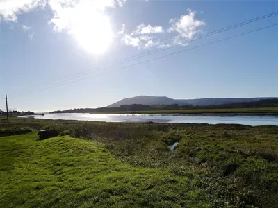 a view of a river with the sun in the sky at Branta Cottage in Dumfries