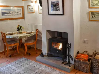 a dining room with a table and a fireplace at Swinside Cottage in Ennerdale Bridge