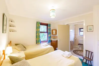 a hotel room with two beds and a bathroom at Laghead Cottage in Gatehouse of Fleet