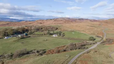 an aerial view of a field with a winding road at Laghead Cottage in Gatehouse of Fleet