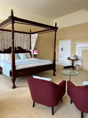 a bedroom with a canopy bed and two chairs at Moresby Hall Country House Hotel in Whitehaven