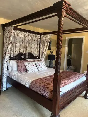 a wooden canopy bed with pillows on it in a bedroom at Moresby Hall Country House Hotel in Whitehaven