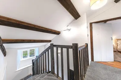 a staircase in a house with white walls and wooden beams at Knott House Farm in Keswick