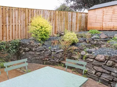 a garden with two benches and a wooden fence at 1 Millbank in Keswick
