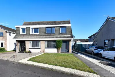 a house with two cars parked in front of it at Links Golf Villa in Troon