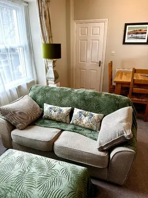 a living room with a green couch with pillows at A charming luxury apartment! in Portinscale