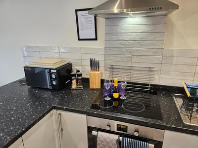 a kitchen with a black counter top with a microwave at Carlisle City Centre. The Foremans Residence. in Carlisle
