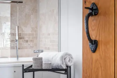 a bathroom with a shower with a towel on a stool at Kilnmark Bothy in Thornhill
