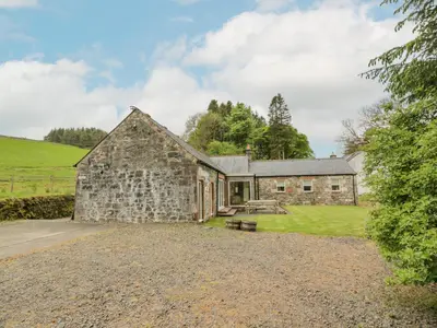 an old stone barn with a picnic table in front of it at Kilnmark Bothy in Thornhill