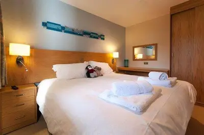 a large white bed with a teddy bear sitting on it at Keswick Bridge 19, within walking distance of Keswick town centre, strictly no pets in Keswick