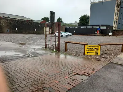 a parking lot with a yellow sign on a fence at Lowther Apartment - 2 Bedrooms - Sleeps 4 in Whitehaven