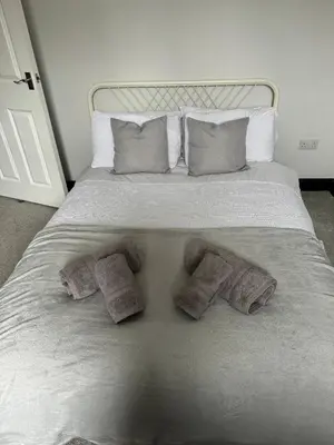 a white bed with three pillows and three towels at Lowther Apartment - 2 Bedrooms - Sleeps 4 in Whitehaven