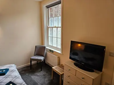 a bedroom with a flat screen tv and a chair at Carlisle City Centre The Gavel in Carlisle