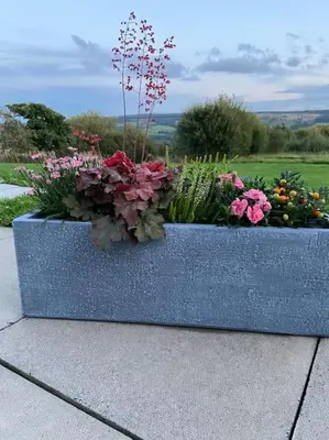 a blue stone planter filled with flowers and plants at Lanfine View 1 at Loudoun Mains with Hot Tub in Newmilns