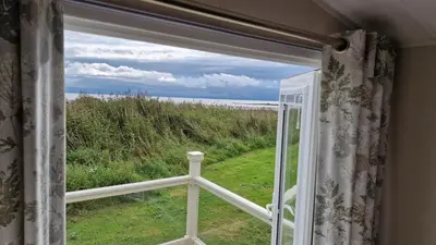 a window with a view of the ocean at Seaside Heaven - Southerness Caravan Rental in Mainsriddle