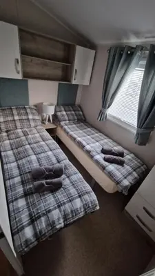 two beds in a small room with a window at Seaside Heaven - Southerness Caravan Rental in Mainsriddle