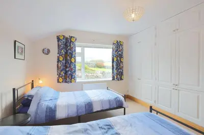 a bedroom with two beds and a window at Teapot Cottage in Newton Stewart